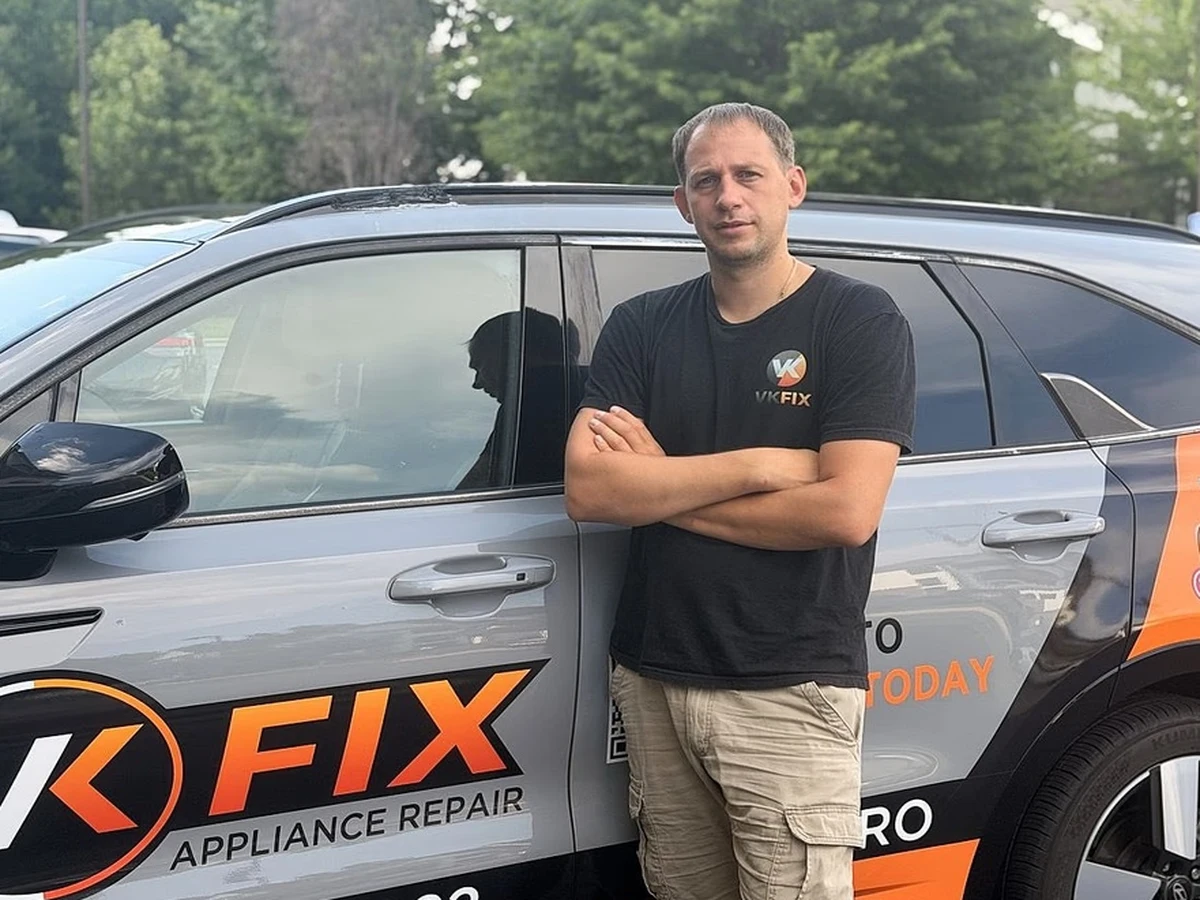 VKFIX appliance repair technician standing beside the company service vehicle